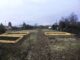 Blick in einen Schrebergarten mit drei Beeteinfassungen aus Holz.