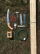 Material und Werkzeug, das man für das Errichten einer Rankhilfe aus Holz und Draht benötigt, liegt auf einem Rasen.