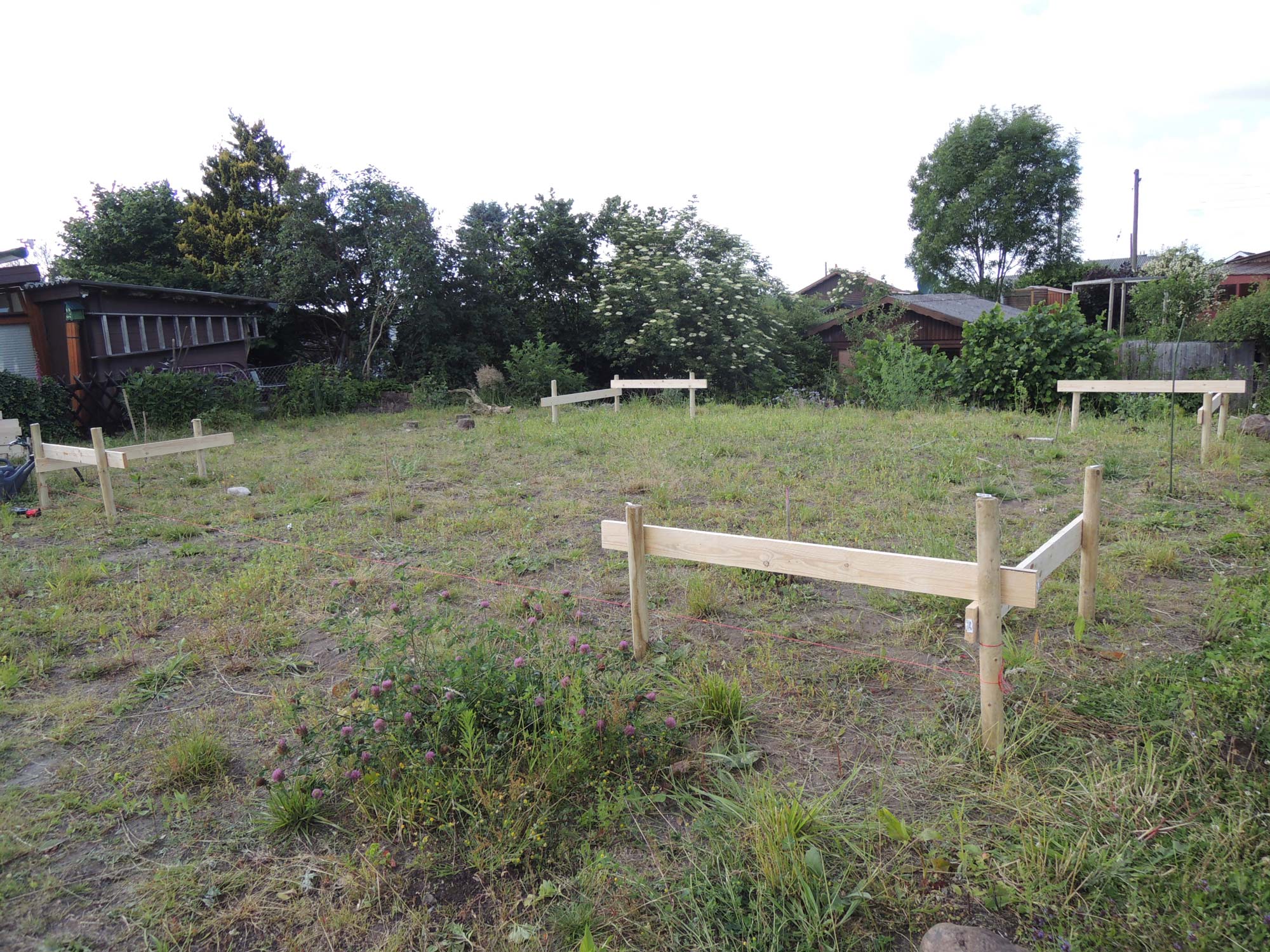 Ein fertiges Schnurgerüst steht in einem Garten.