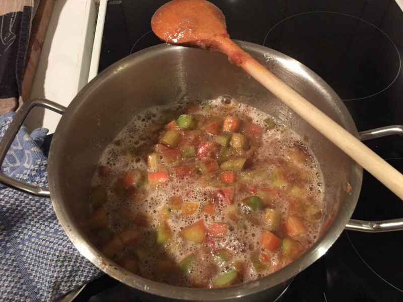 Rhabarberkompott köchelt in einem Topf auf einem Herd.