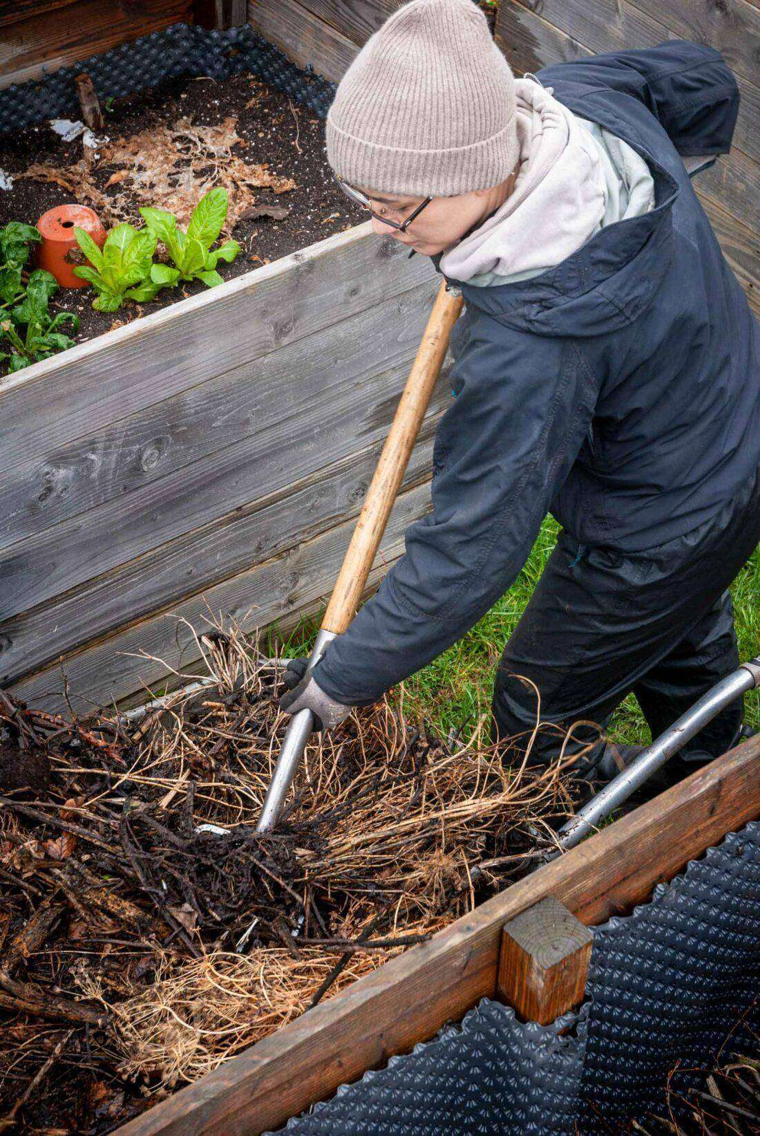 Deborah Hucht befüllt ein Hochbeet mit Kompost und Staudenschnitt. 