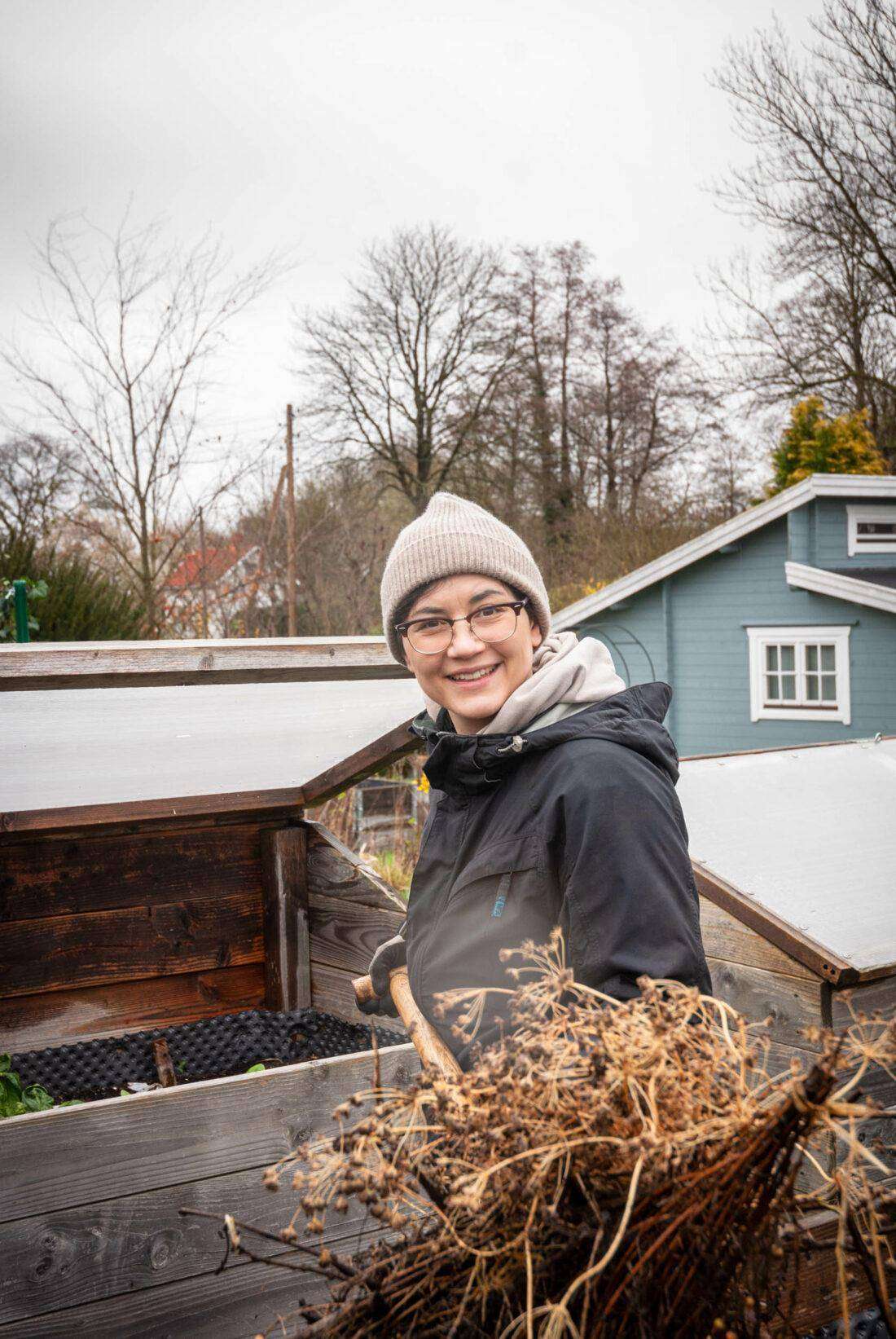 Porträt von Deborah Hucht beim Befüllen eines Hochbeets mit unreifem Kompost. 