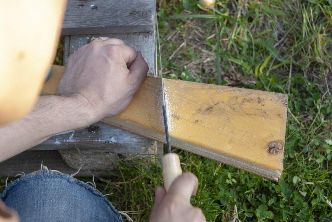 Gartengerätehalter selber bauen: Ein Stück Holz wird zurechtgesägt.