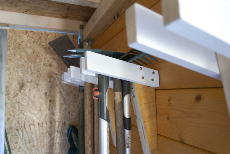 Gartengerätehalter selber bauen – Halterungen sin din einer Gartenlaube aus Holz an der Wand montiert.