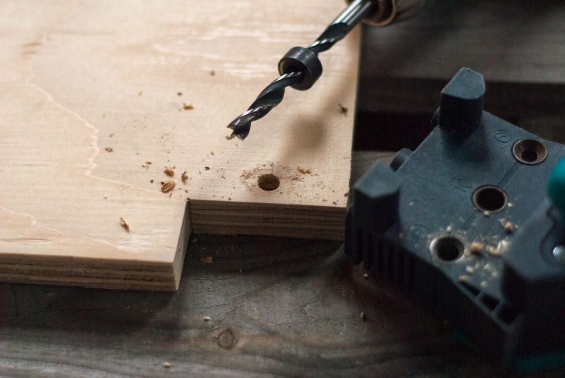 DIY-Küchenzeile: Zu sehen ist eine Holzplatte, in deren Ecke mit einem Holzbohrer ein Loch gebohrt wurde. 