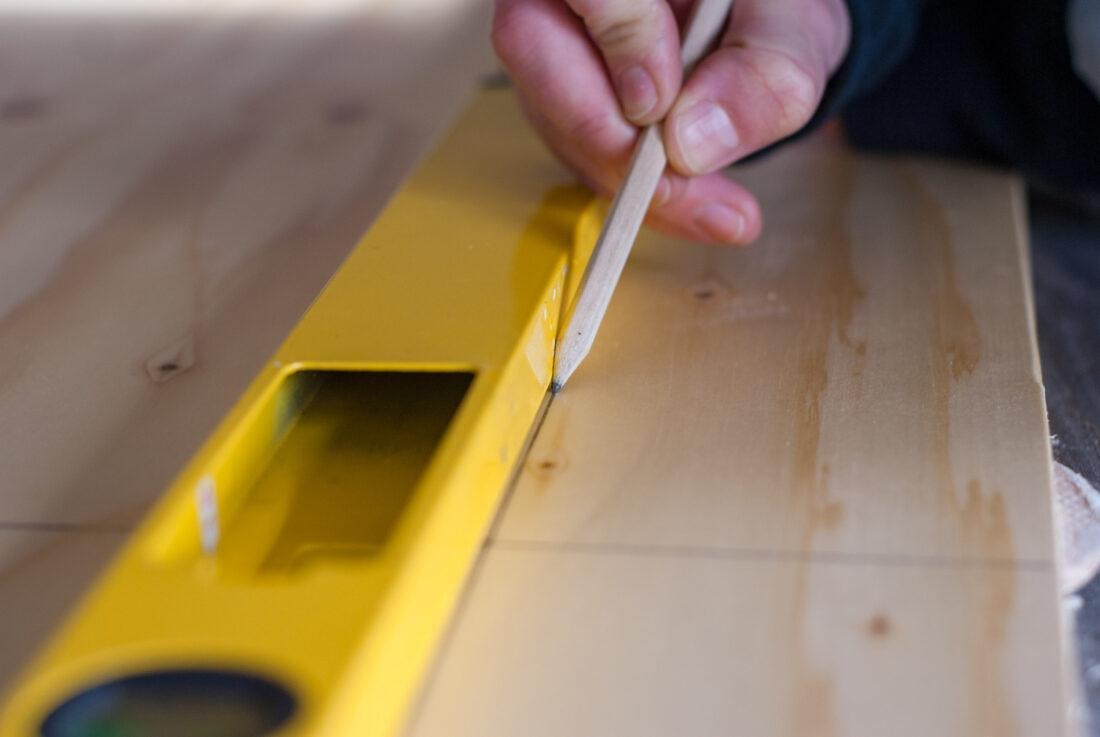 DIY-Küchenzeile: Mit Bleistift wird eine Linie auf ein Stück Holz gezeichnet. 