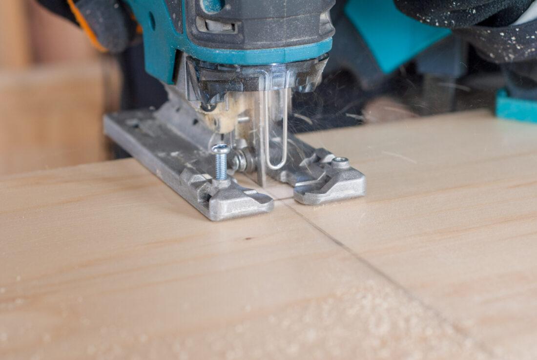 DIY-Küchenzeile: Eine Holzplatte wird mit einer Stichsäge zurechtgesägt. 