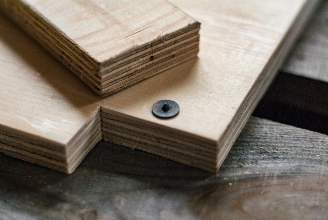 DIY-Küchenzeile: auf einer Holzplatte liegt eine Holzleiste. In der Platte steckt eine Zentrierspitze, auf der Leistenkante sieht man einen eingeritzten Punkt. 