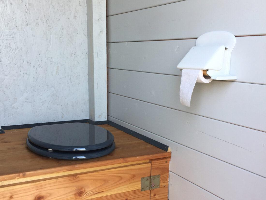 Toilettenrollernhalter aus Keramik in einem Toilettenraum in einem Gartenhaus.
