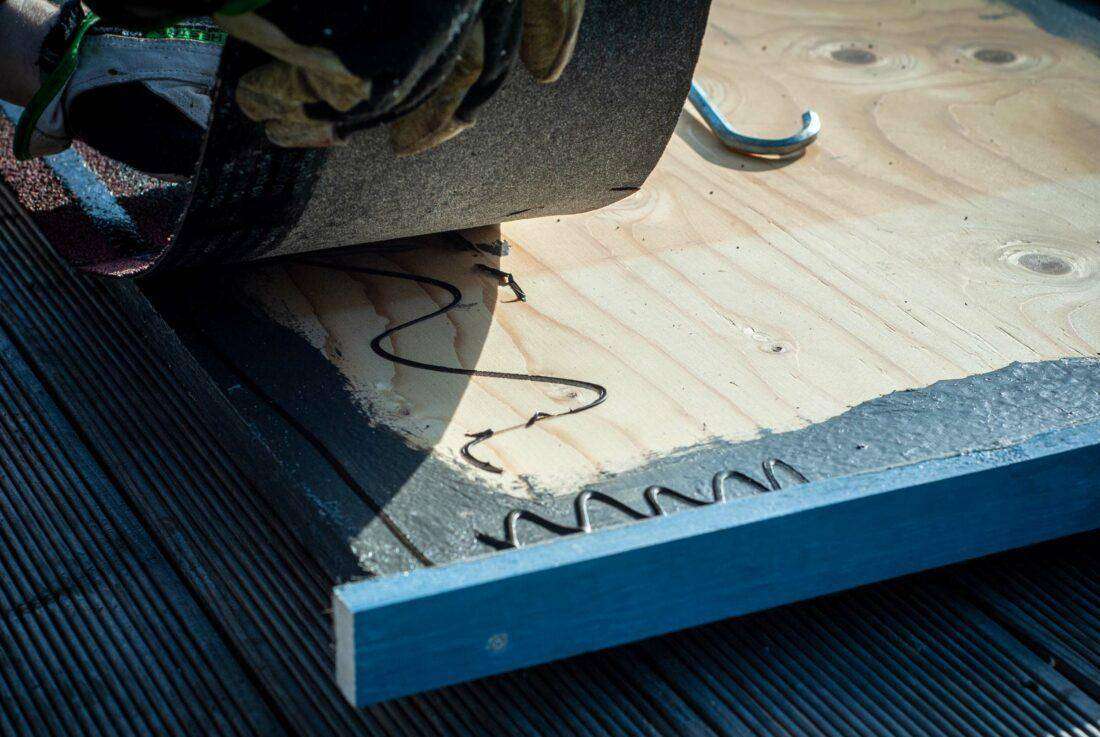 Ein Mann klebt Dachpappe auf das Dach einer DIY-Außenküche.