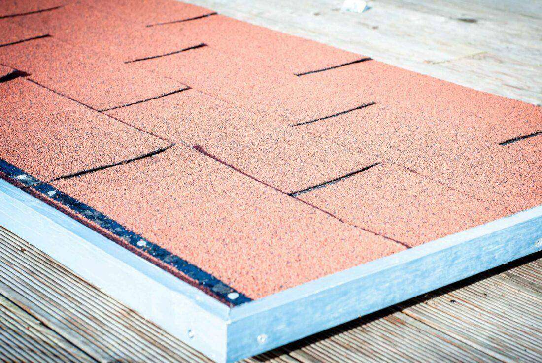 Ein Dachteil einer Außenküche zum Selberbauen liegt auf einer Terrasse aus Holz. 