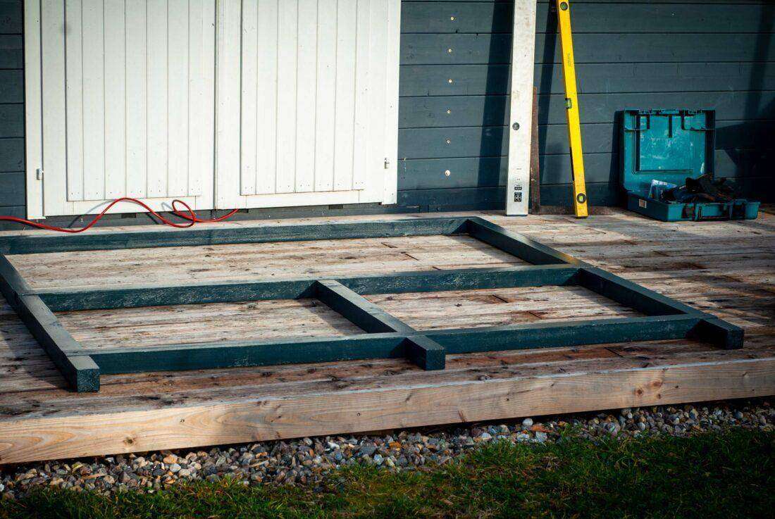 Außenküche selber bauen: Ein Rhamen aus Kanthölzern liegt auf einer Terrasse aus Holz. 
