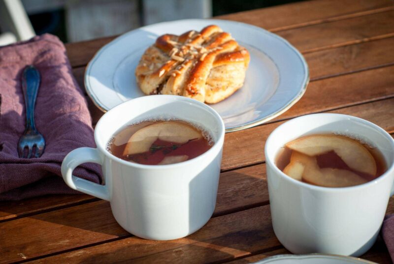 Auf einem Gartentisch stehen zwei Becher mit Quittenpunsch.