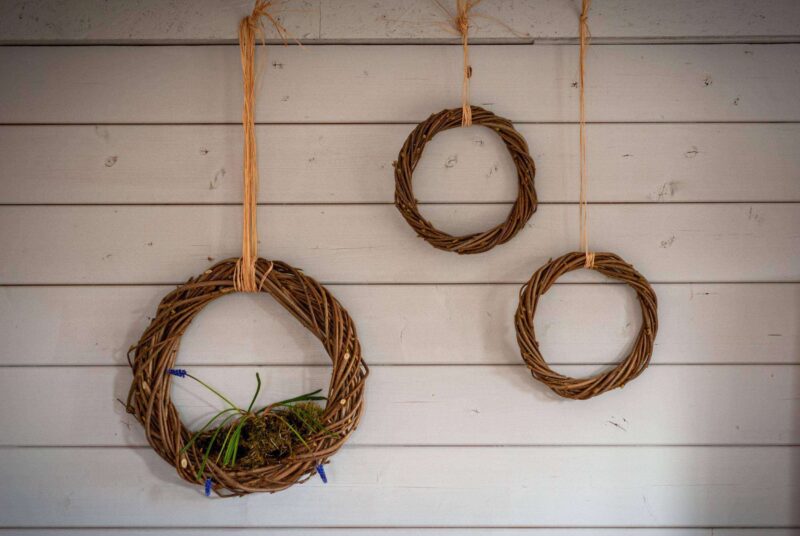 Türkranz selber binden: drei Kränze aus Haselnuss-Stecken hängen an einer Wand.