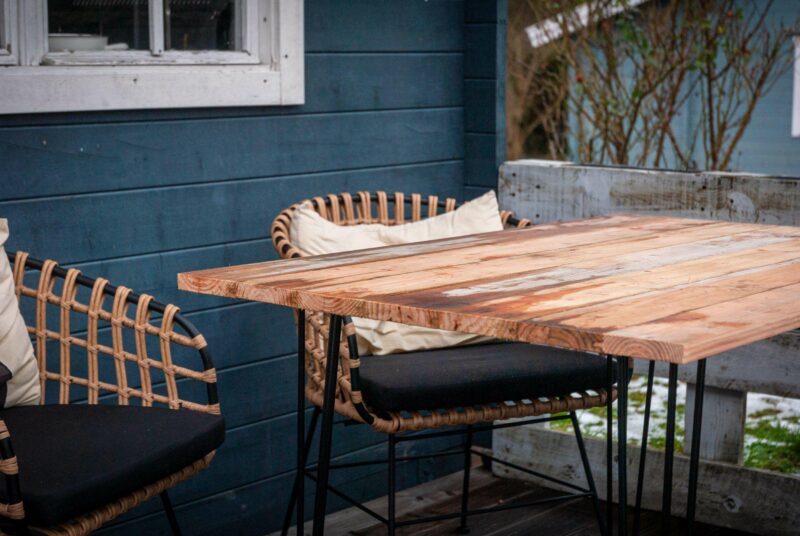 Gartentisch selber bauen: ein fertiger Tisch steht auf einer Terrasse vor einer Gartenlaube.