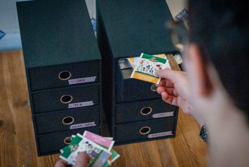 Saatgut lagern: Eine Frau sortiert Saatgut in eine Kommode.