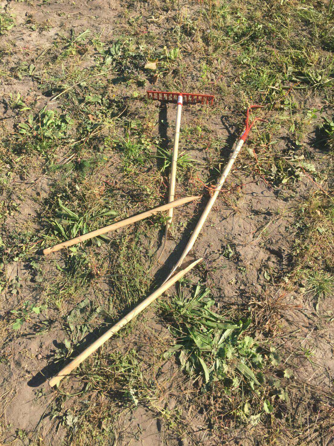 Nachhaltiges Gartenwerkzeug: zerbrochene Werkzeuge liegen auf einer Ackerfläche. 