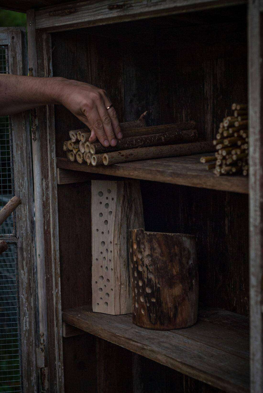 Ein Mann befüllt ein selbst gebautes Insektenhotel. 
