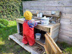 Ein Kind spielt in einer selbst gebauten Matschküche.