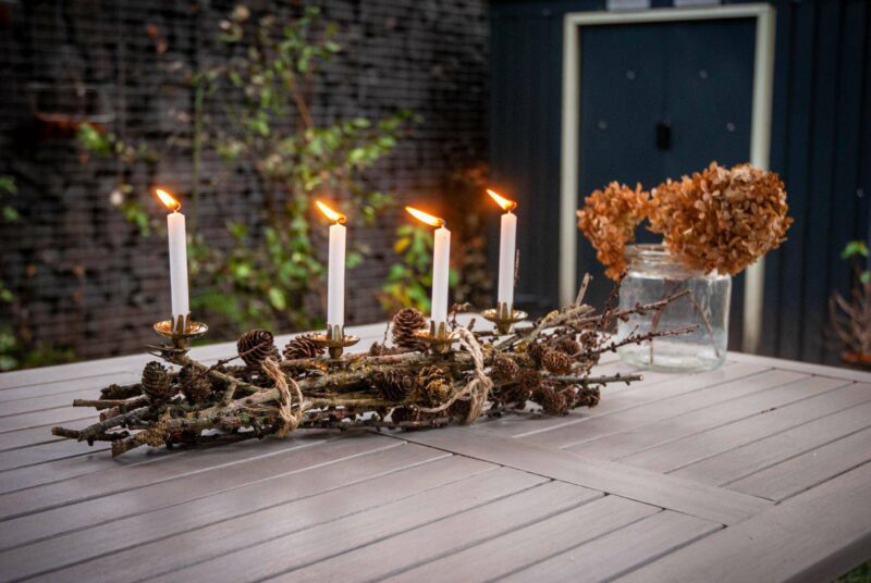 Ein Adventsgesteck aus Lärchenzweigen steht auf einem Tisch.