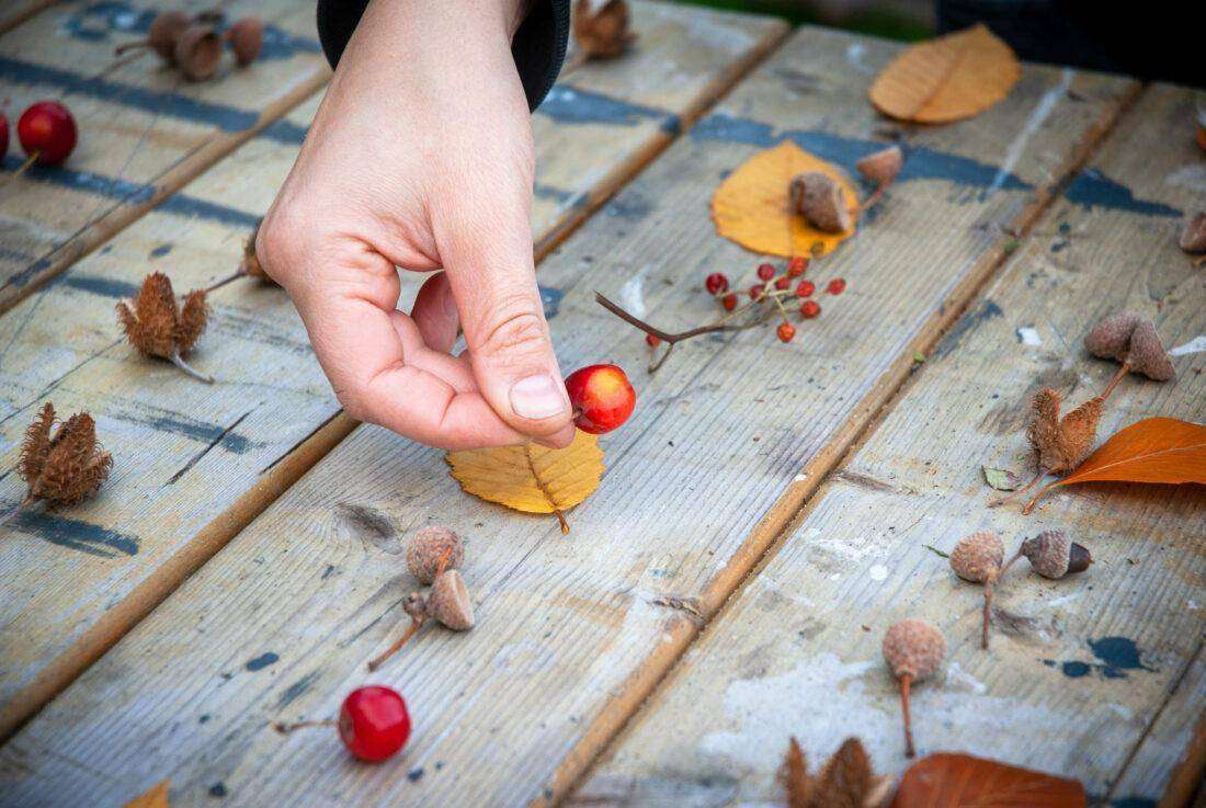 Herbstliche Deko selber machen: eine Frau arrangiert Früchte und Blätter für einen Wandbehang.