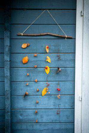 Herbst-Deko in Form eines Wandteppichs hängt an einer Gartenlaube.