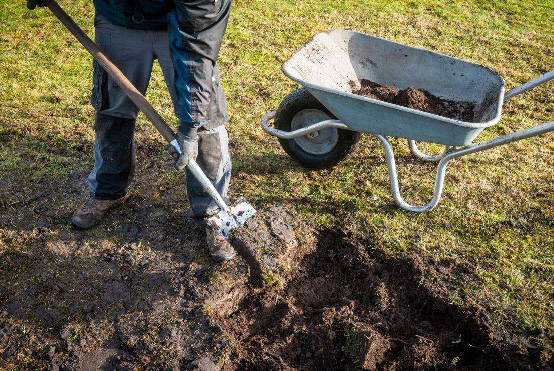 Ein Mann gräbt Grassoden aus, um ein Trockenbeet anzulegen. 