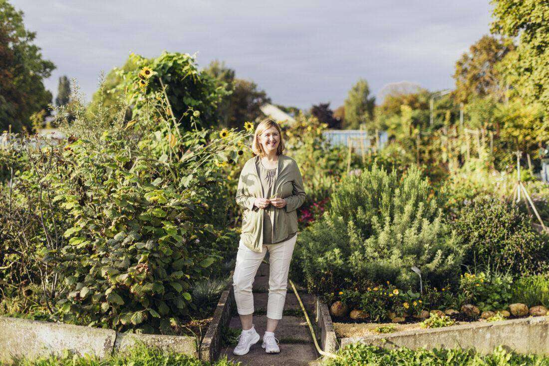 Porträt von Buchautorin Doris Kampas in einem üppig bewachsenen Garten.