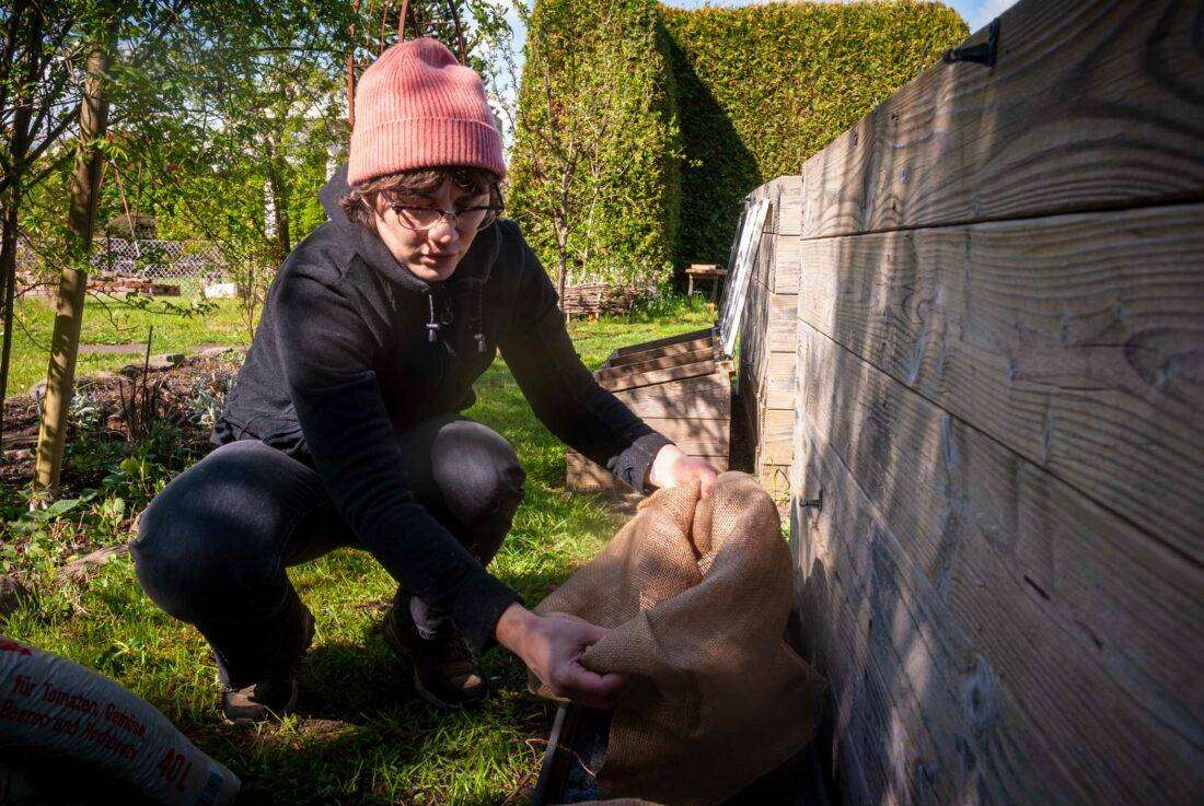 Eine Frau bereitet die Pflanzsäcke vor und krempelt sie um.