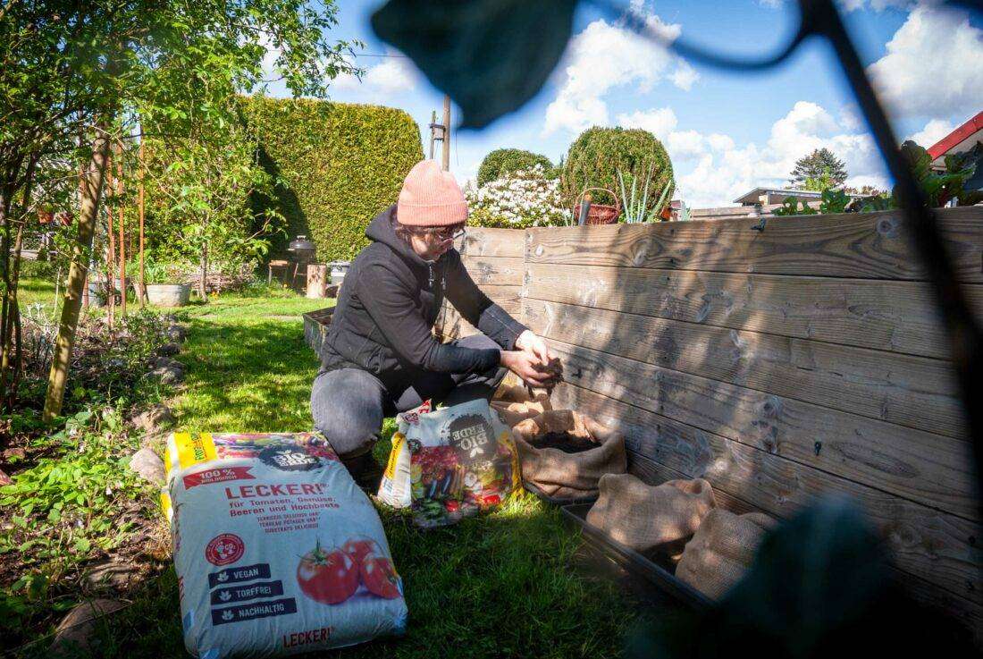 Eine Frau füllt Erde in die vorbereiteten Säcke