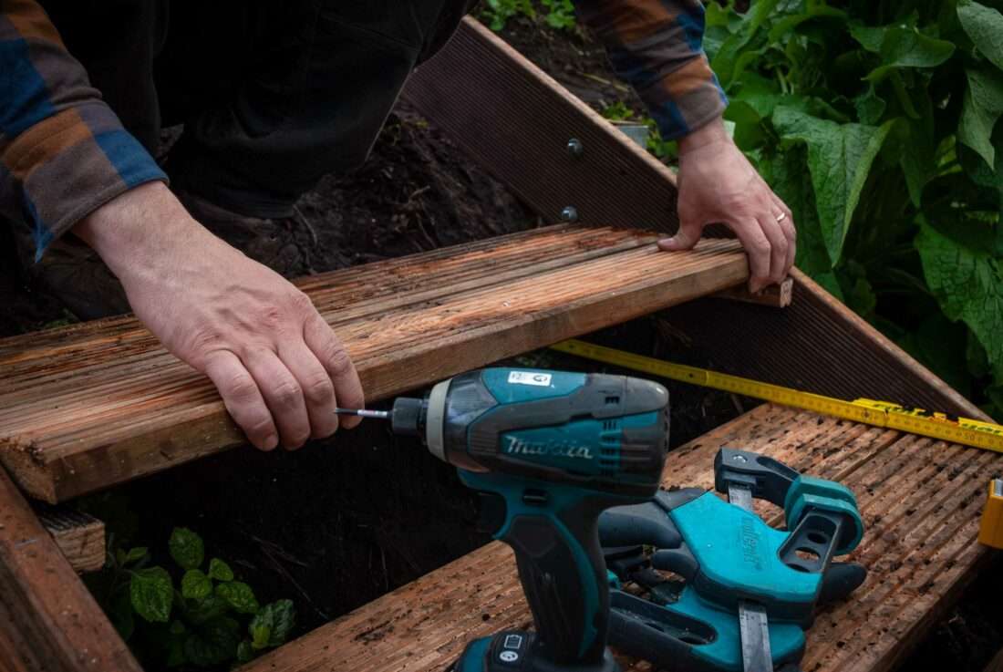 Ein Mann passt weitere Holzbretter als Treppenstufen an.