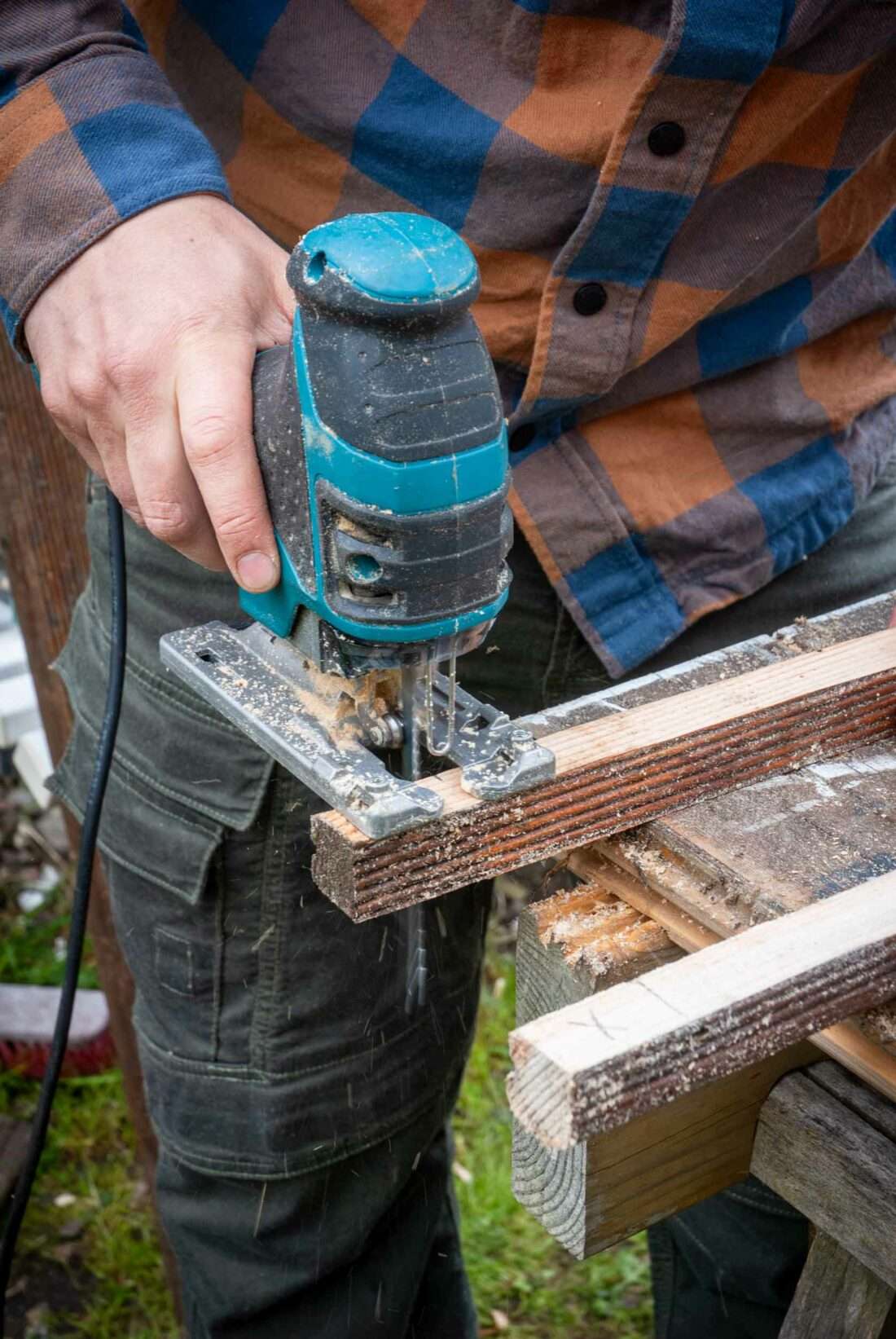 Ein Mann sägt mit der Stichsäge ein Hölzchen zurecht.