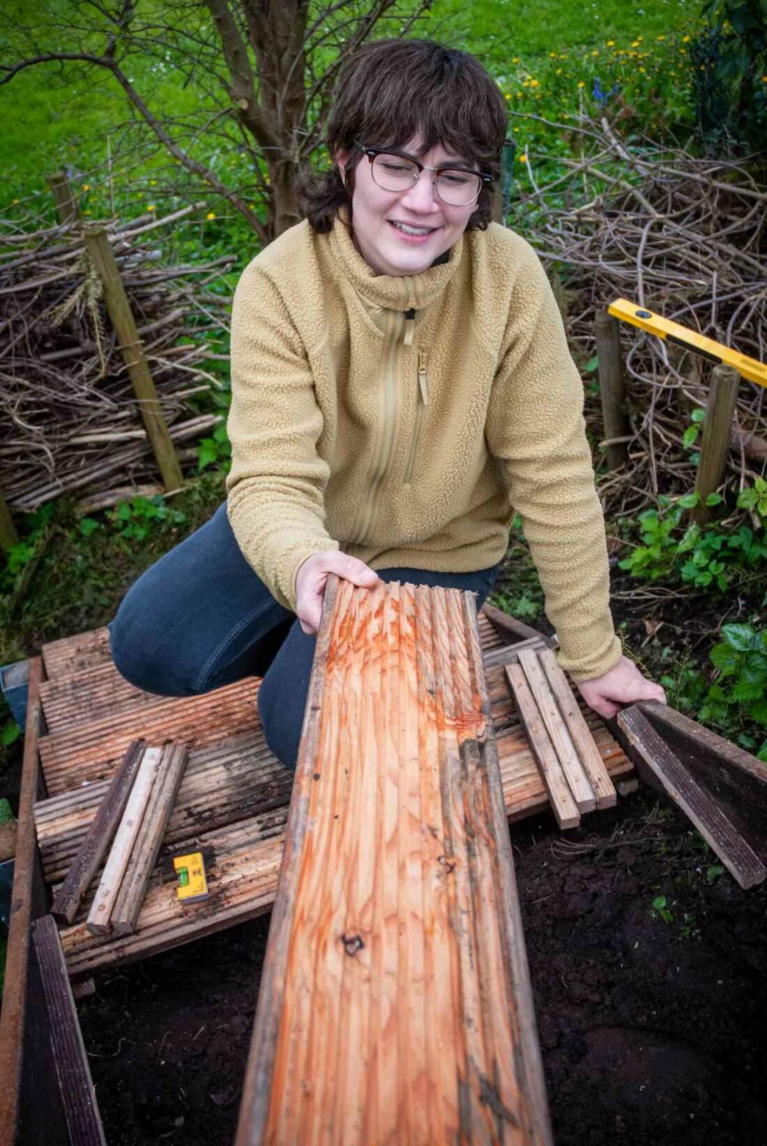 Eine Frau nimmt ein Brett für eine Treppenstufe einer selbst gebauten Treppe entgegen.