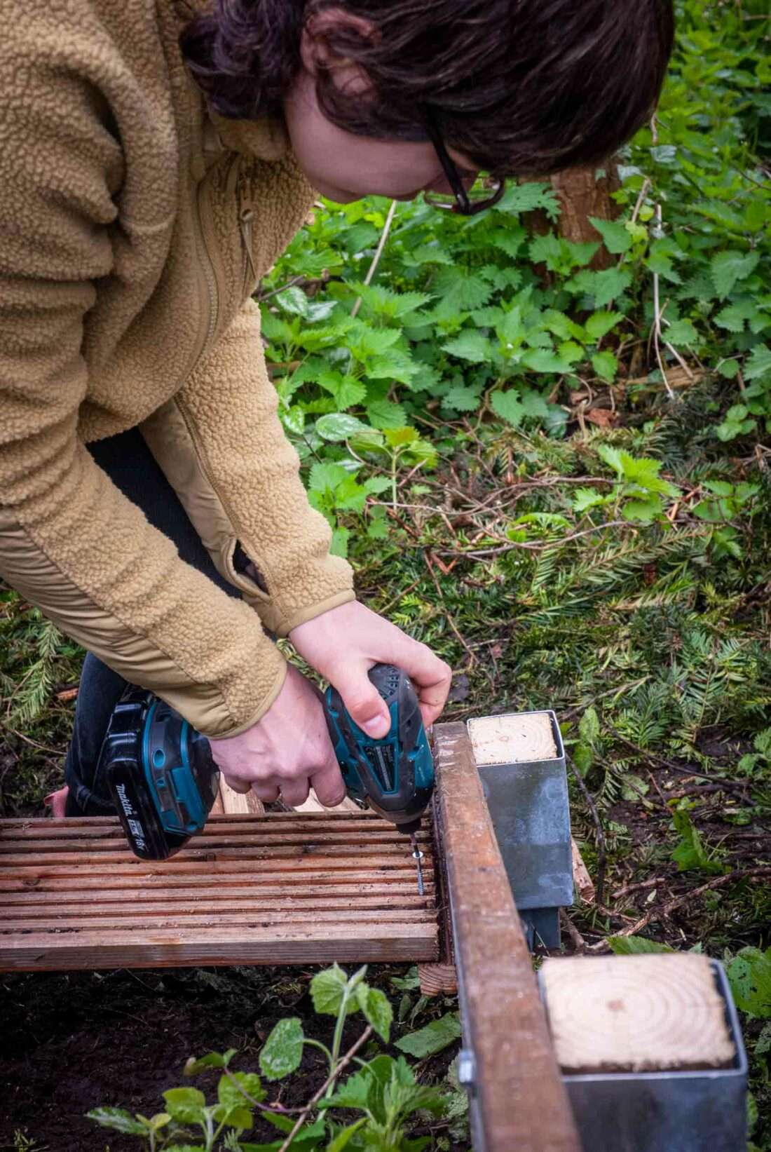 Eine Frau schraubt eine Stufe einer selbst gebauten Holztreppe an.
