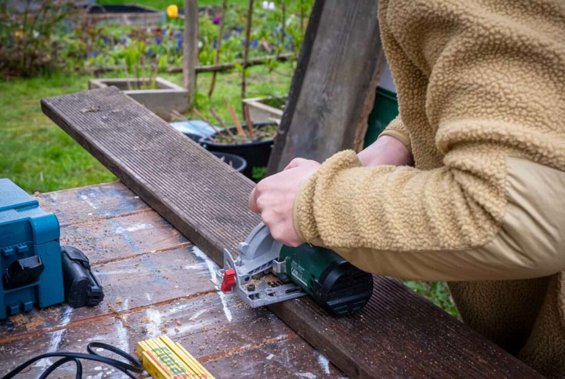 Eine Frau sägt eine Stufe für eine DIY-Holztreppe zu.