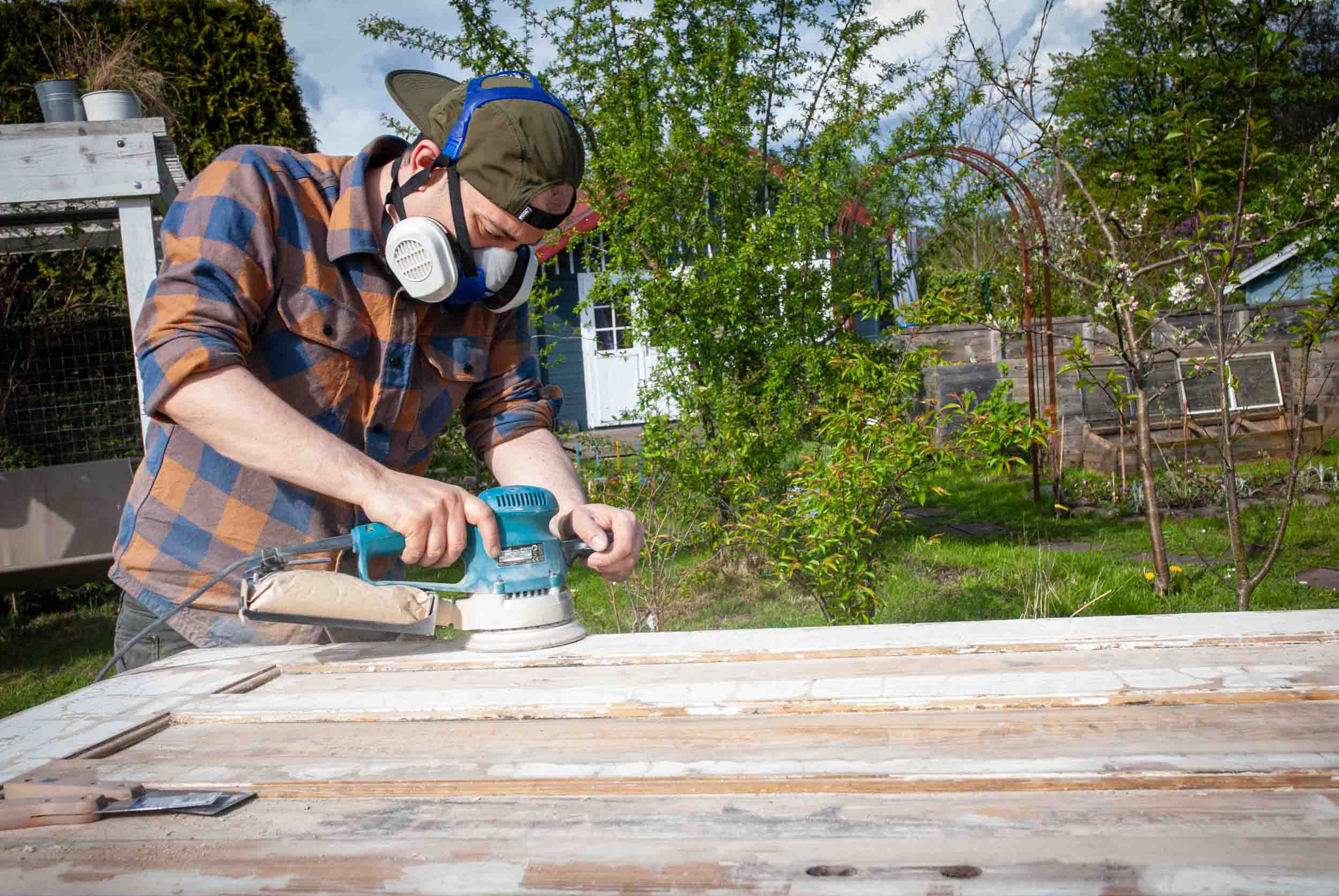 Ein Mann schleift eine alte Tür ab, aus der ein Klapptisch gebaut werden soll.