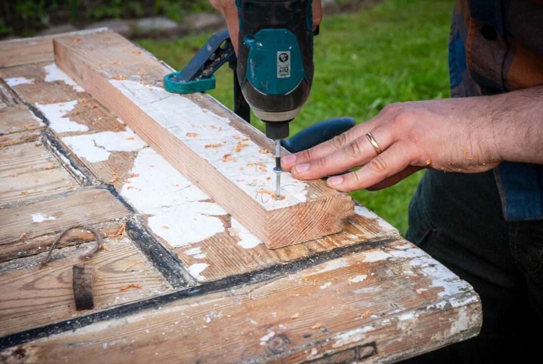 Detailansicht eines Holzes, das unter eine Tischplatte geschraubt wird, um dort Tischbeine zu montieren.