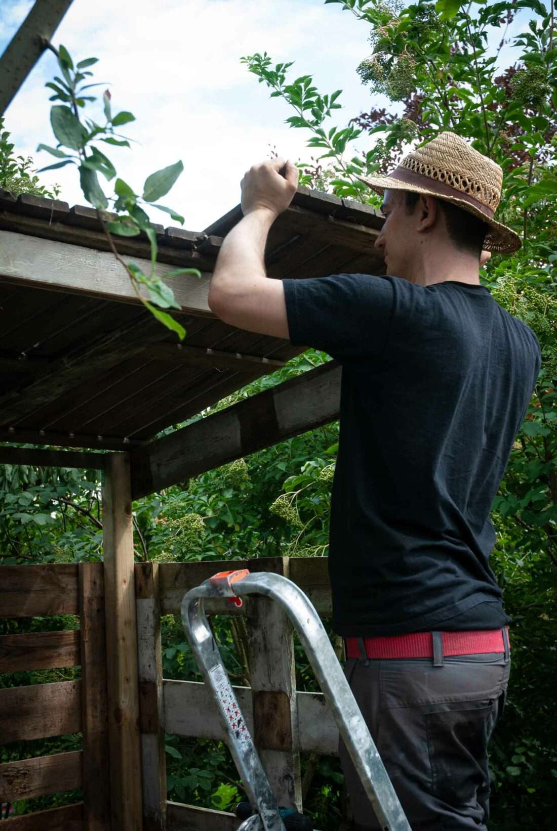 Ein Mann montiert das Dach eines selbst gebauten Spielhauses.