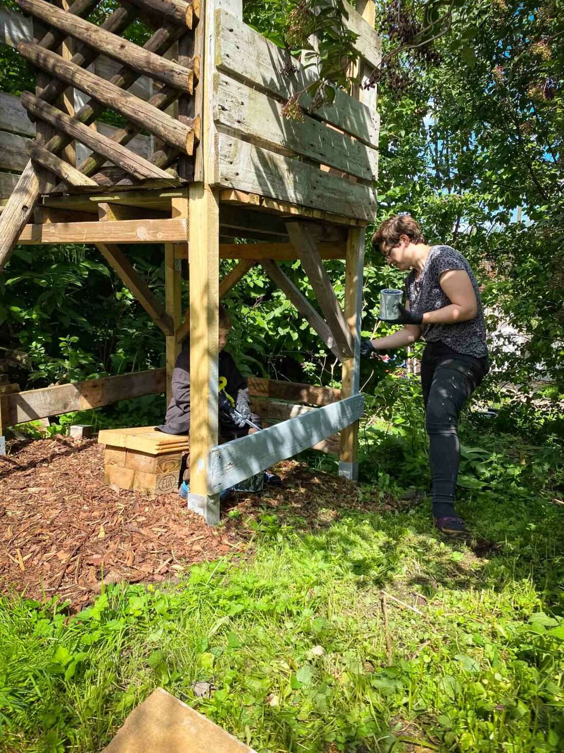 Eine Frau lackiert ein selbst gebautes Spielhaus.