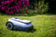 ECOVACS Mähroboter GOAT A1600 RTK vor einem blühenden Rhododendron.