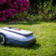 ECOVACS Mähroboter GOAT A1600 RTK vor einem blühenden Rhododendron.