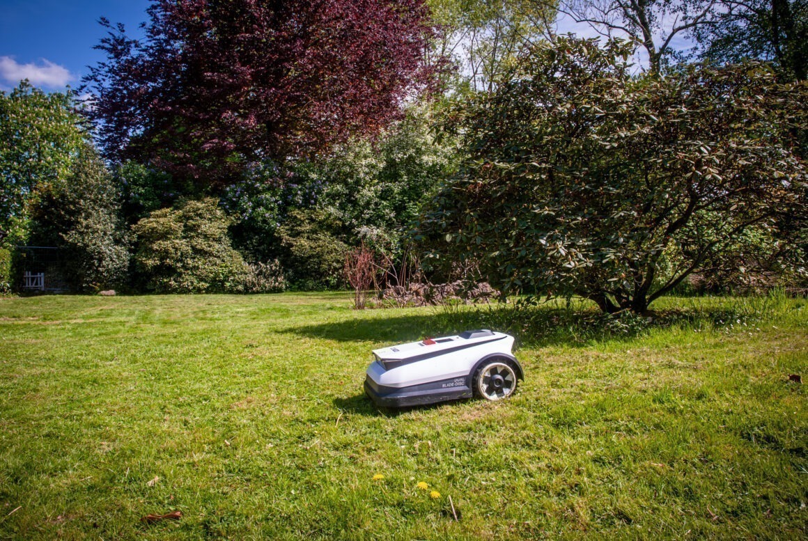 Ein Mähroboter von ECOVACS fährt über eine Rasenfläche. 