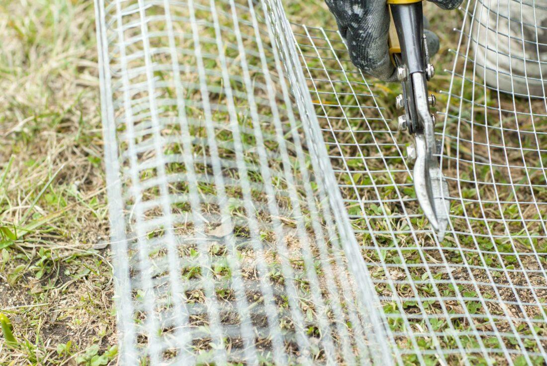Mit einer Blechschere wird ein Stück Hasendraht für den Einbau in ein Hochbeet zurechtgeschnitten. 
