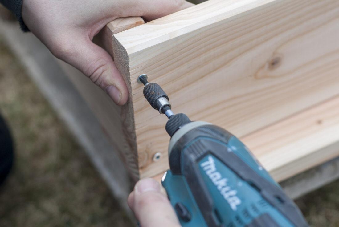 Der untere Rahmen eines selbst gebauten Hochbeets wird montiert. 