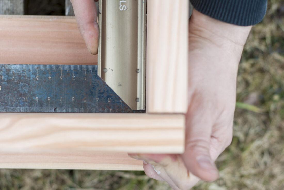 Mithilfe eines Schreinerwinkels wird der Rahmen eines Hochbeets montiert.
