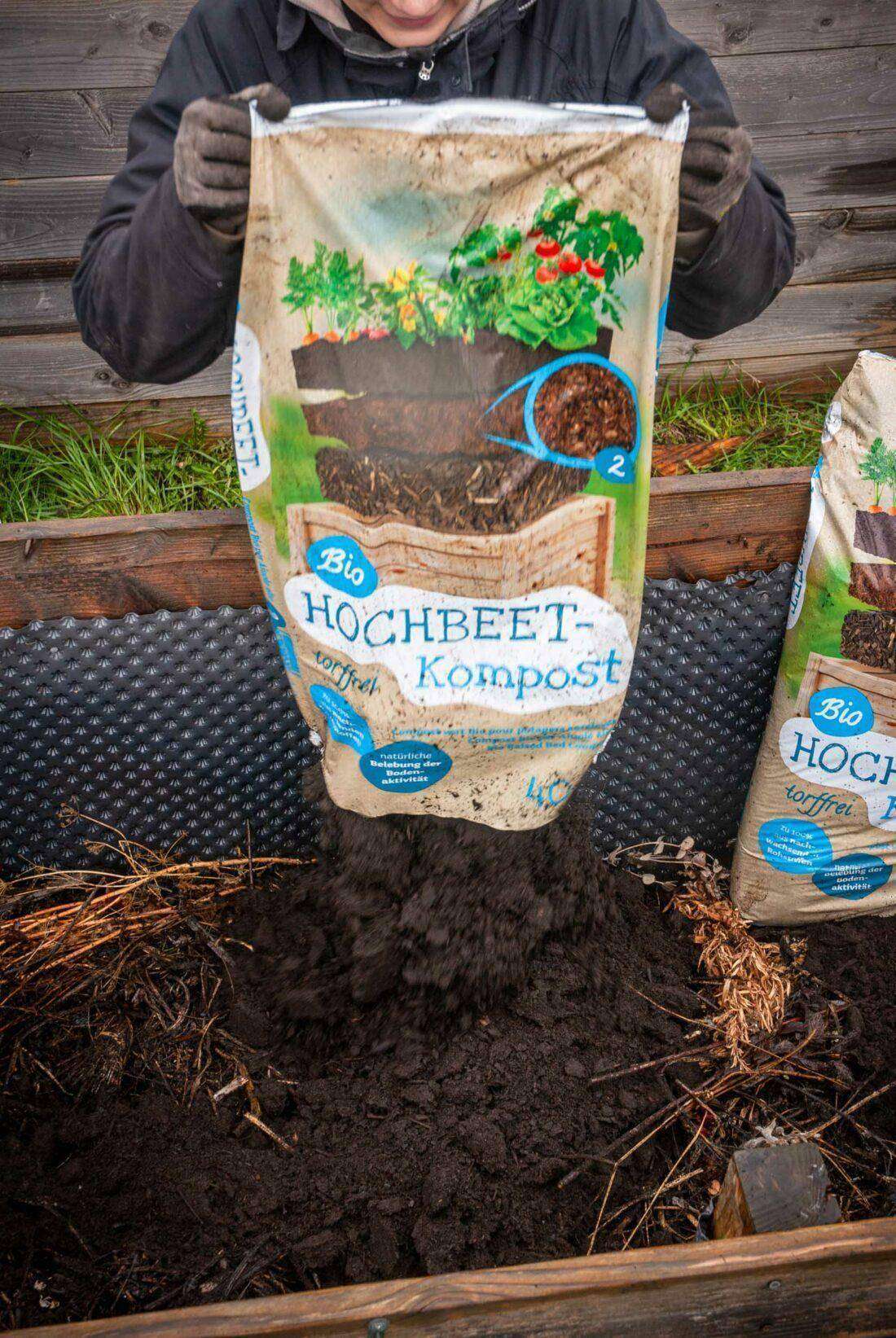 Eine Frau befüllt ein Hochbeet mit Kompost der Marke Floragard. 