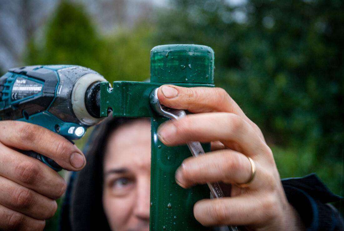 Ein mann montiert die Aufhängung für einen Terrassen-Sichtschutz.