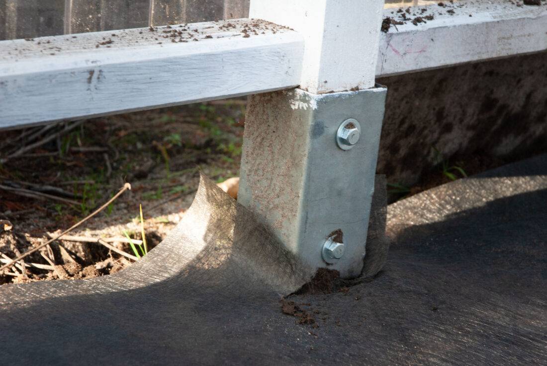 Detailansicht einer Einschlagbodenhülse, die von Unkrautvlies umgeben ist.