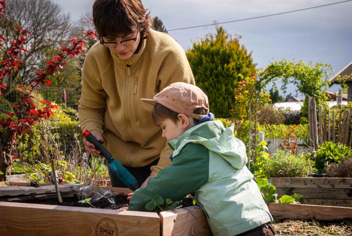 eine Frau und ein Junge bepflanzen ein Hochbeet für Kinder