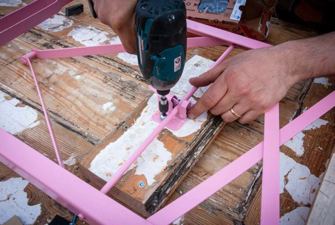 En Mann schraubt ein Tischbein an die Unterseite eines Klapptisches.